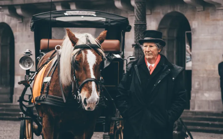 miti-main page about us a man riding a horse drawn carriage in front of a building